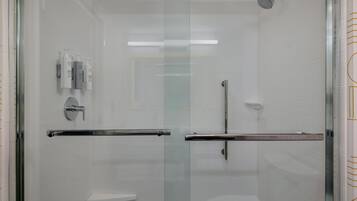 A modern bathroom with a glass-enclosed shower, a toilet, and a vanity with toiletries.