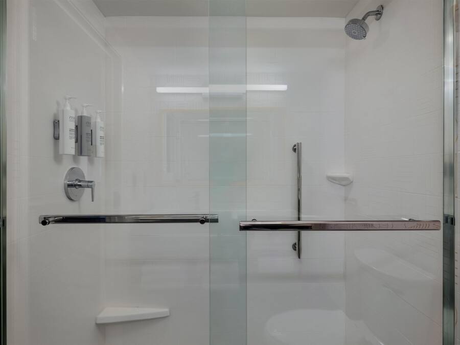 A modern bathroom with a glass-enclosed shower, a toilet, and a vanity with toiletries.