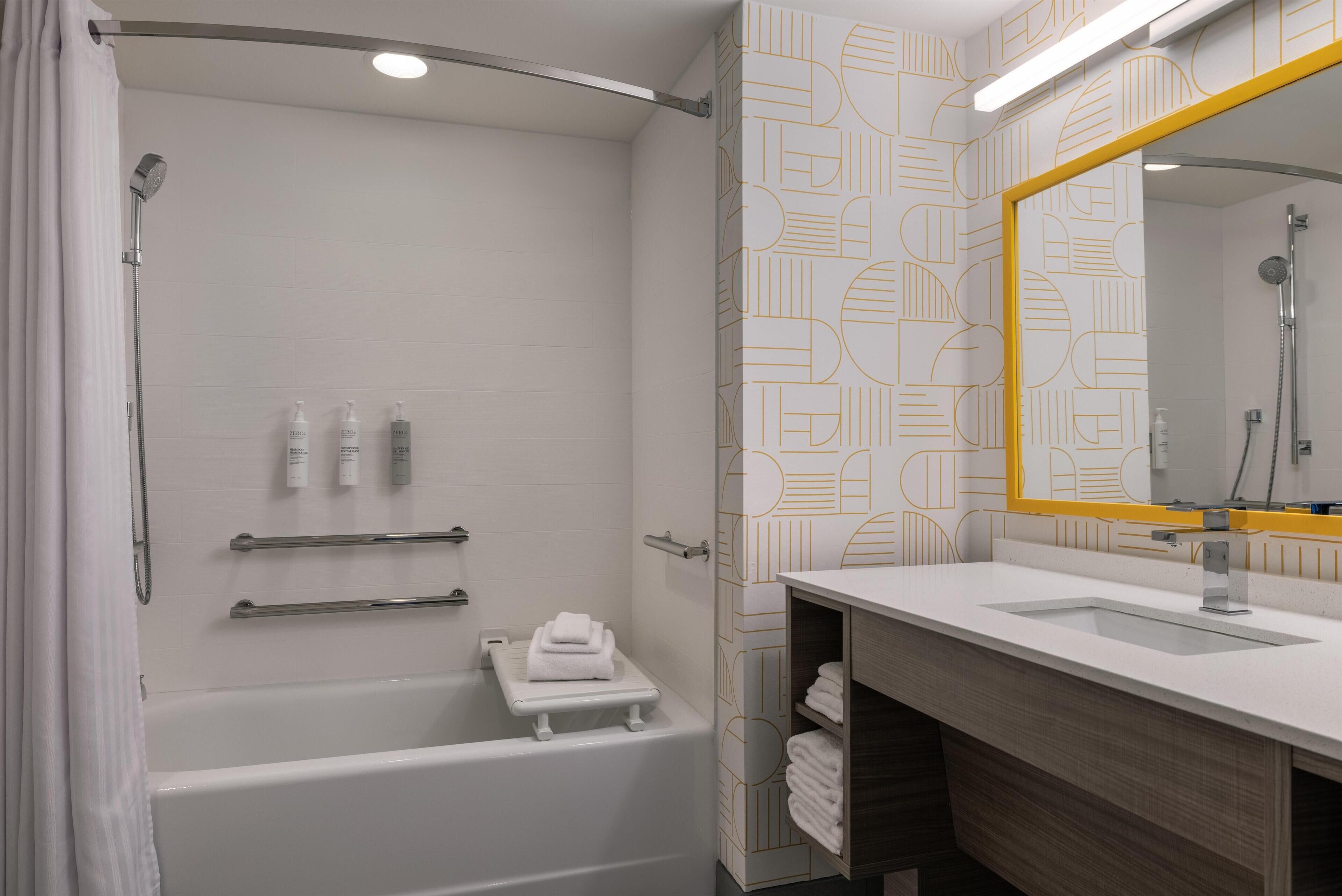 Een moderne badkamer met een badkuip, douche en wastafel met spiegel.