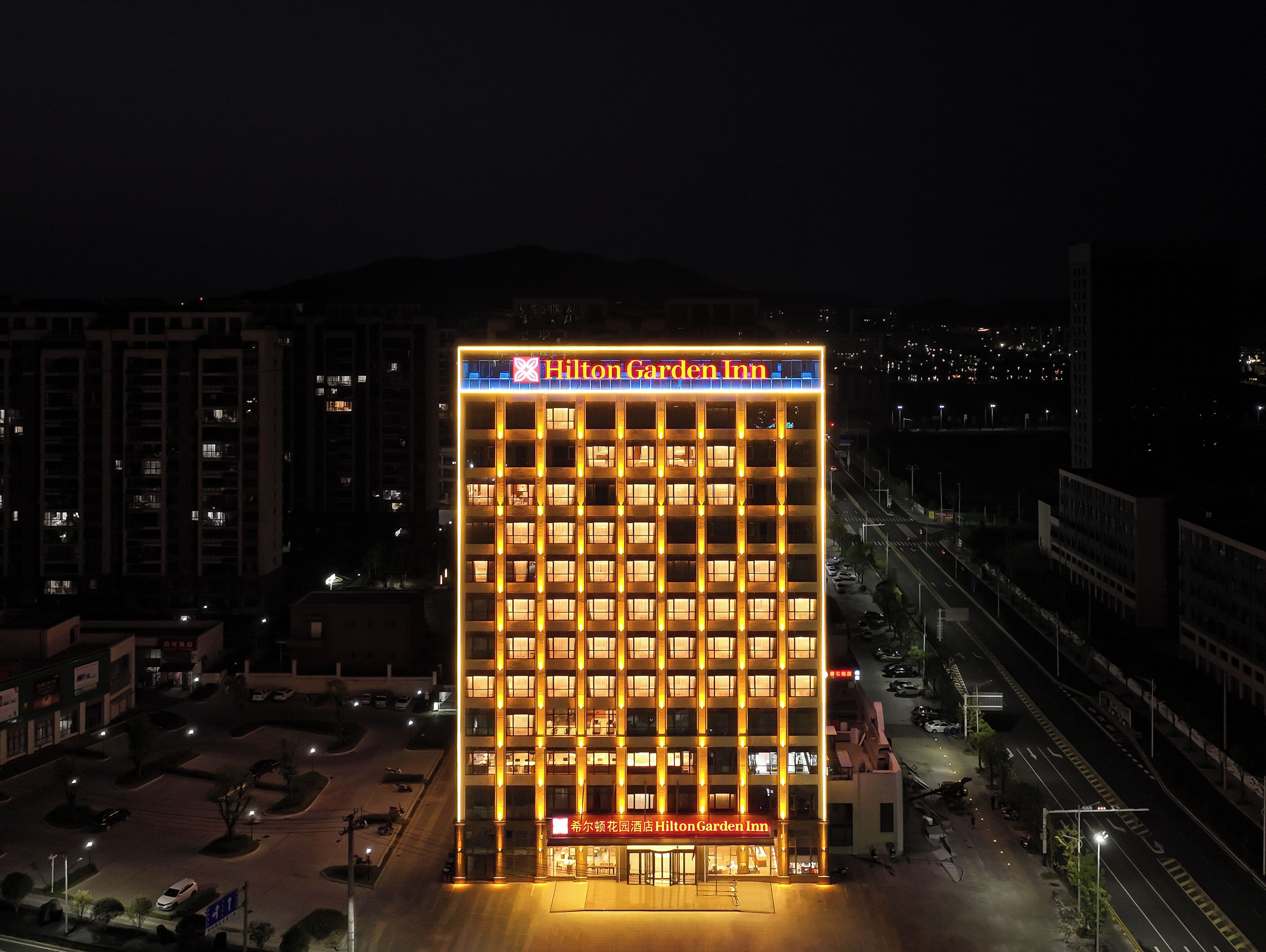 Un edificio de varios pisos con señalización iluminada que dice 'Hilton Garden Inn'.