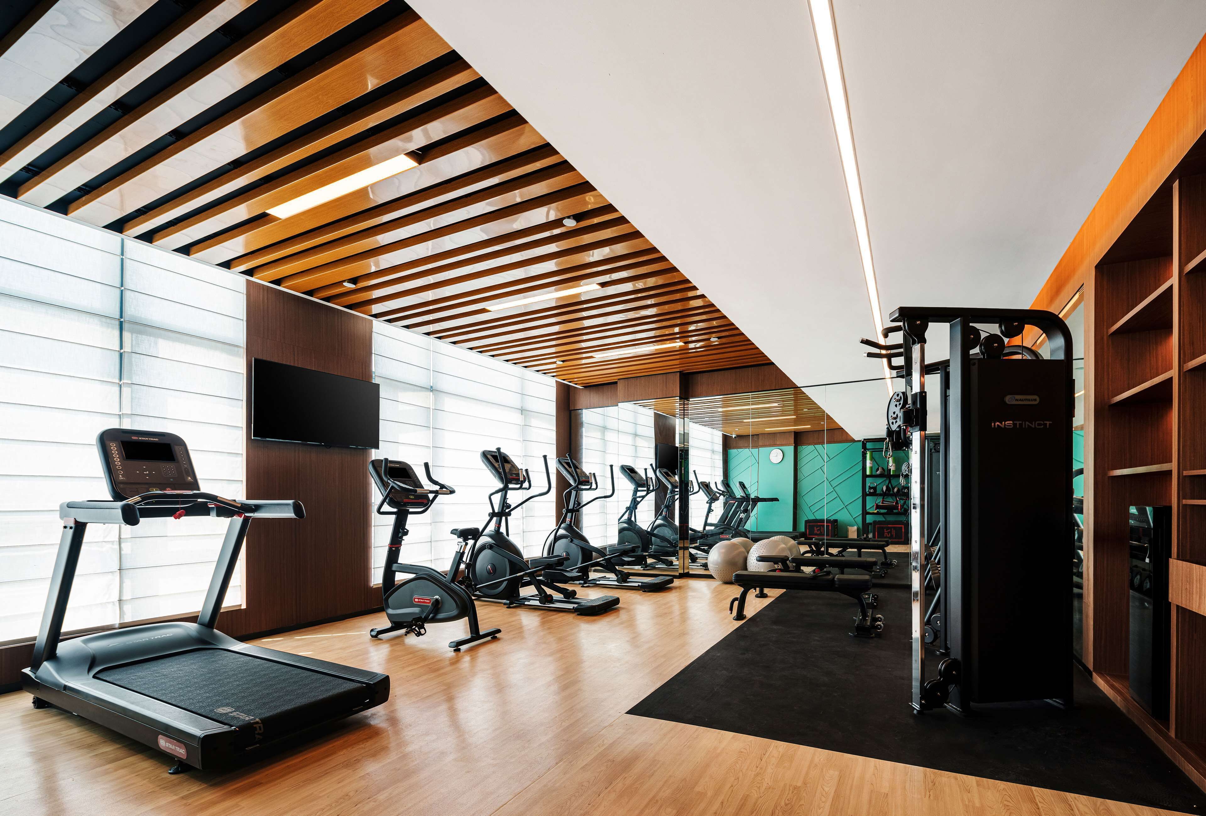 A modern gym with treadmills, elliptical machines, and weightlifting equipment.