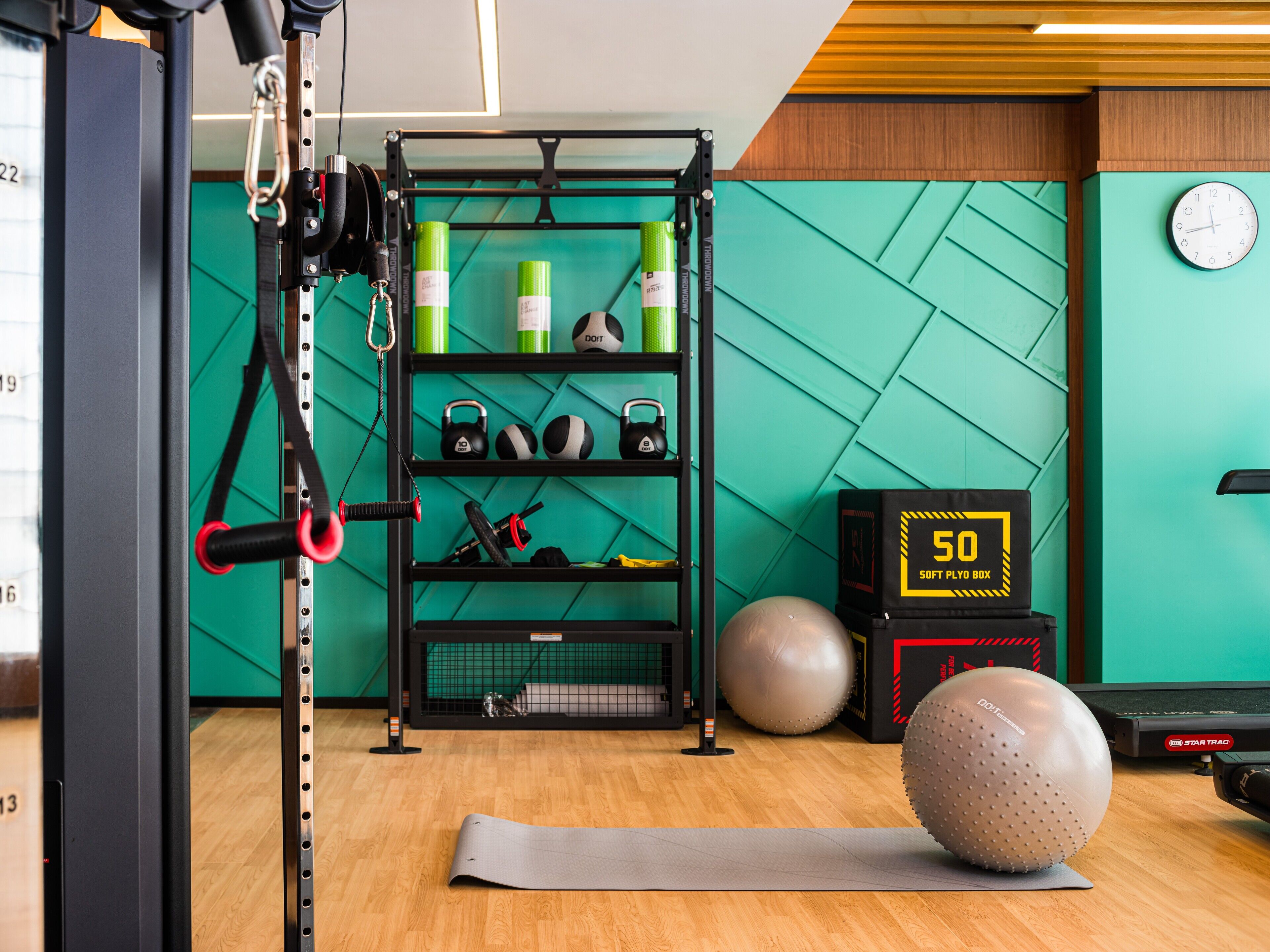 A gym with a pull-up bar, kettlebells, exercise balls, and a digital timer.
