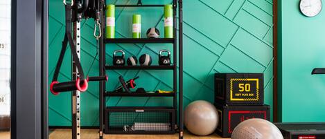 A gym with a pull-up bar, kettlebells, exercise balls, and a digital timer.
