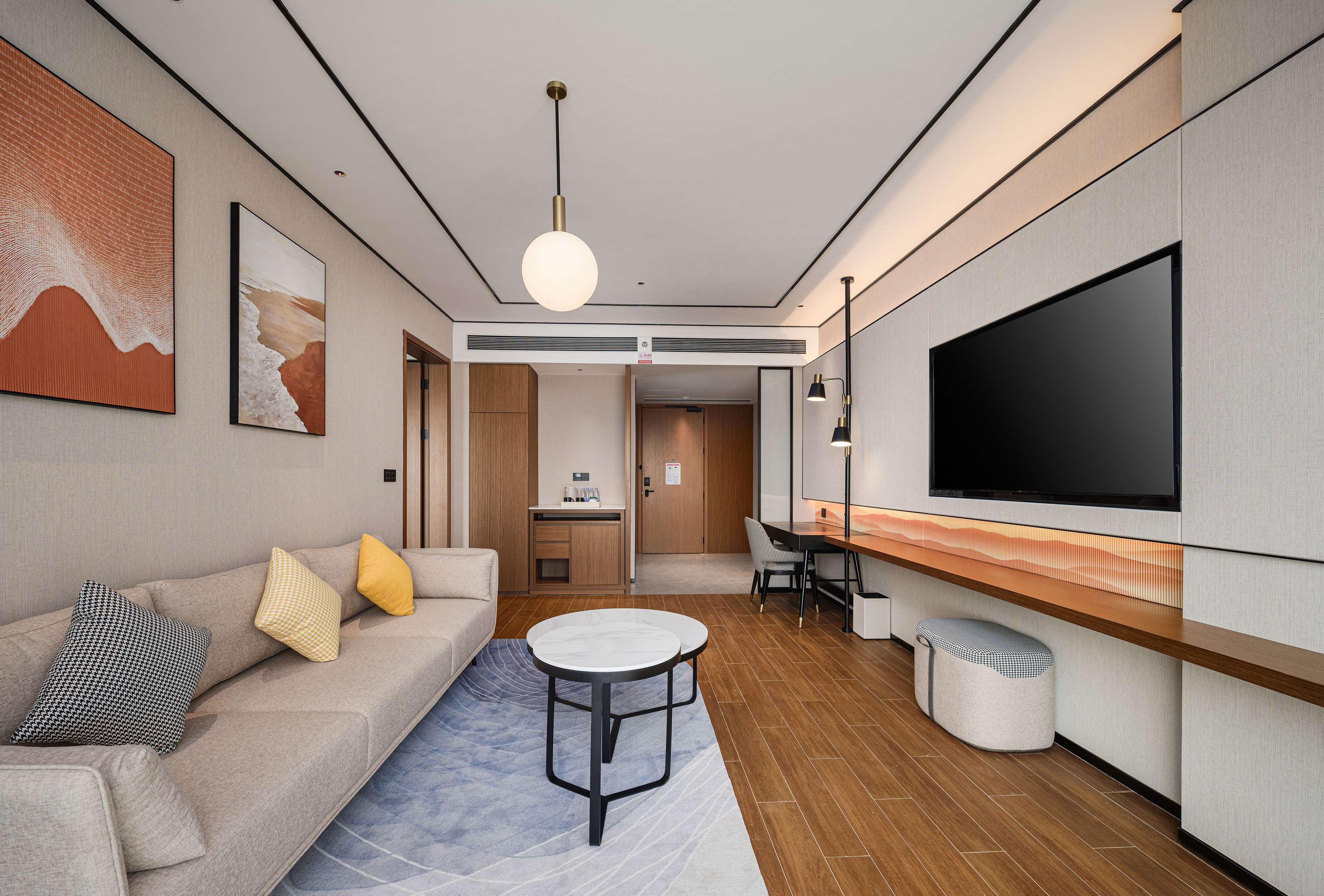A modern living room with a sofa, coffee table, and a flat-screen TV mounted on the wall.