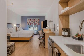 Ein modernes Hotelzimmer mit Bett, Schreibtisch und Küchenzeile.