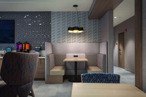 Eine moderne Hotelhalle mit Sitzgelegenheit, bestehend aus einem Tisch und Stühlen, einer Wand mit Muster und einer Deckenleuchte.