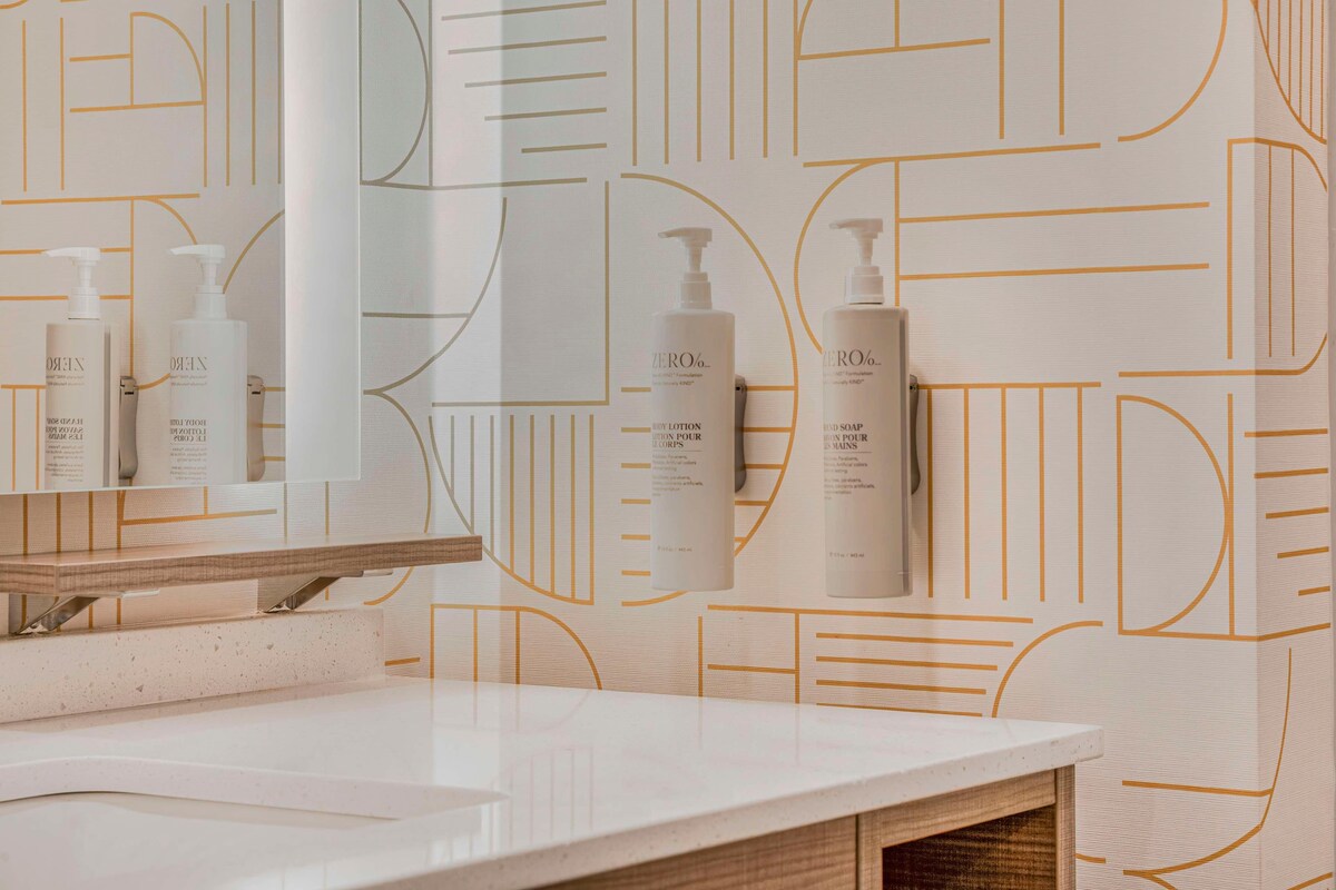 Et badeværelse med en hvid bordplade, et spejl og to flasker Zero% bodylotion og sæbe.