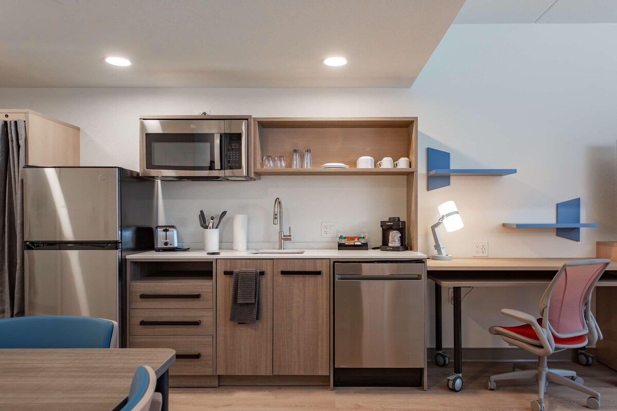 Una cocina moderna con refrigerador, microondas, pileta y cafetera.
