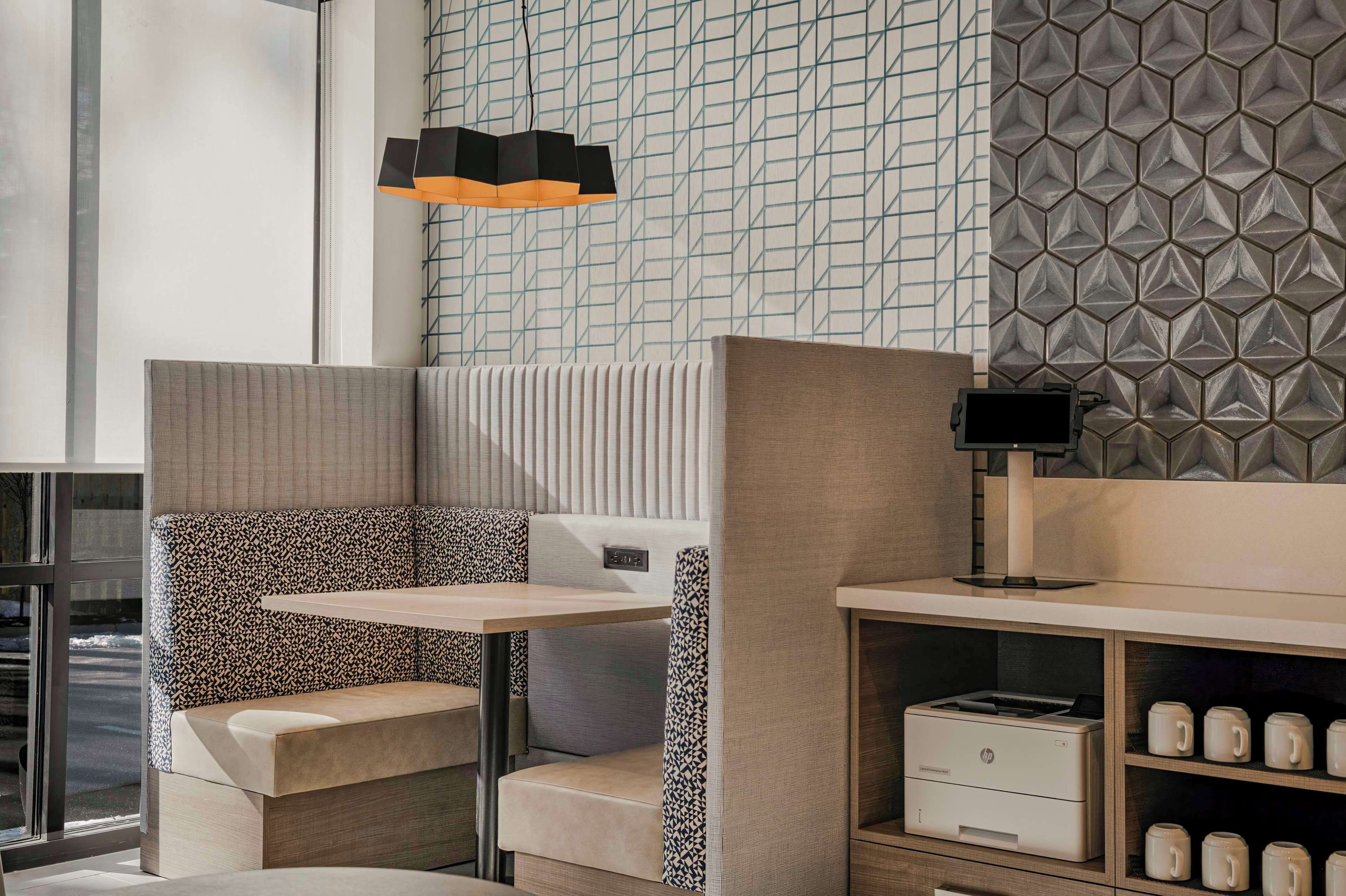 Un área de estar moderna y bien iluminada con una pared decorada, una mesa y una impresora.