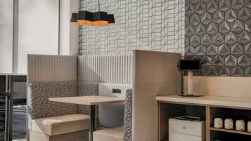 Un área de estar moderna y bien iluminada con una pared decorada, una mesa y una impresora.
