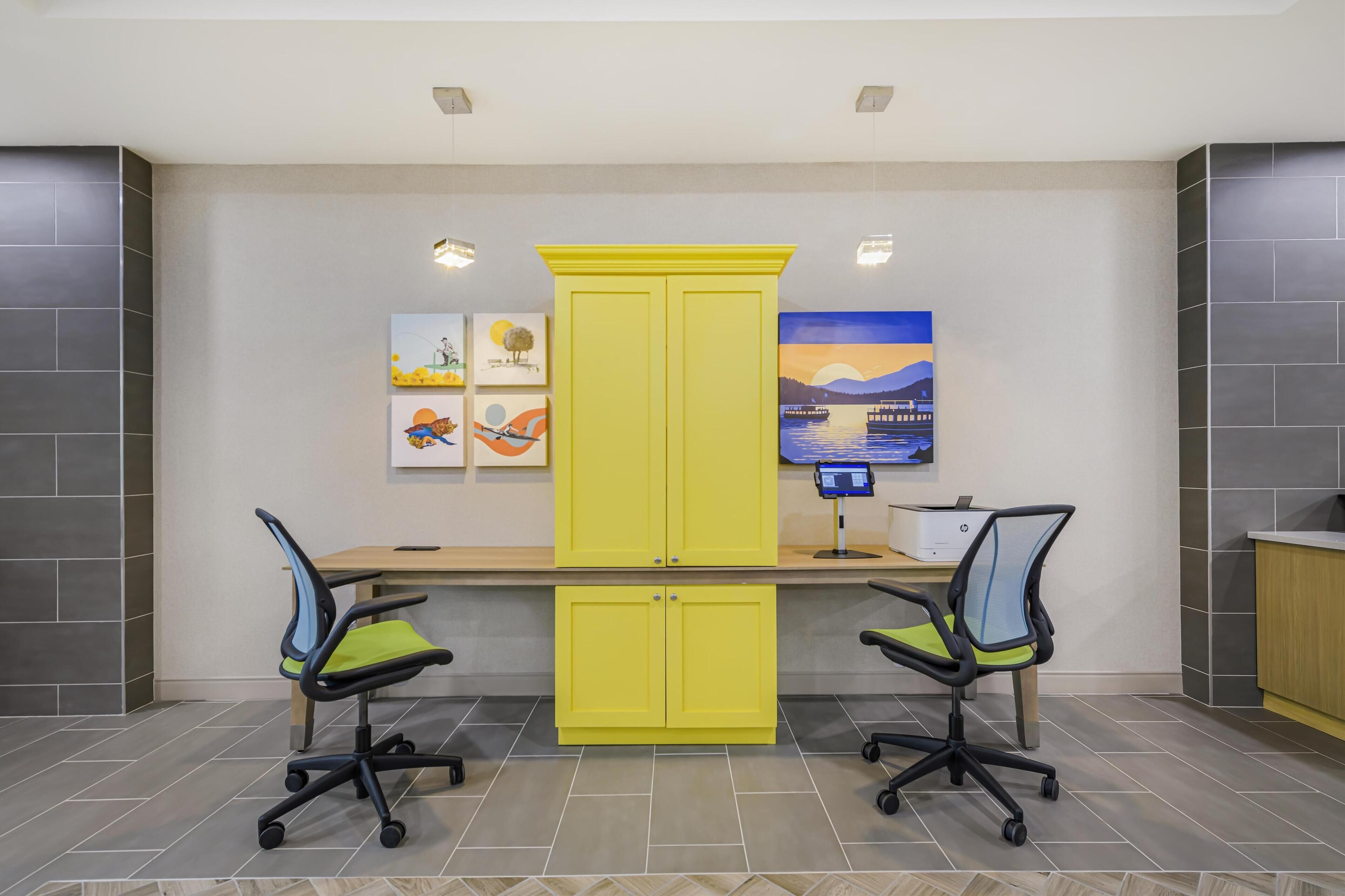 A modern office space with two desks, yellow cabinets, and office chairs.