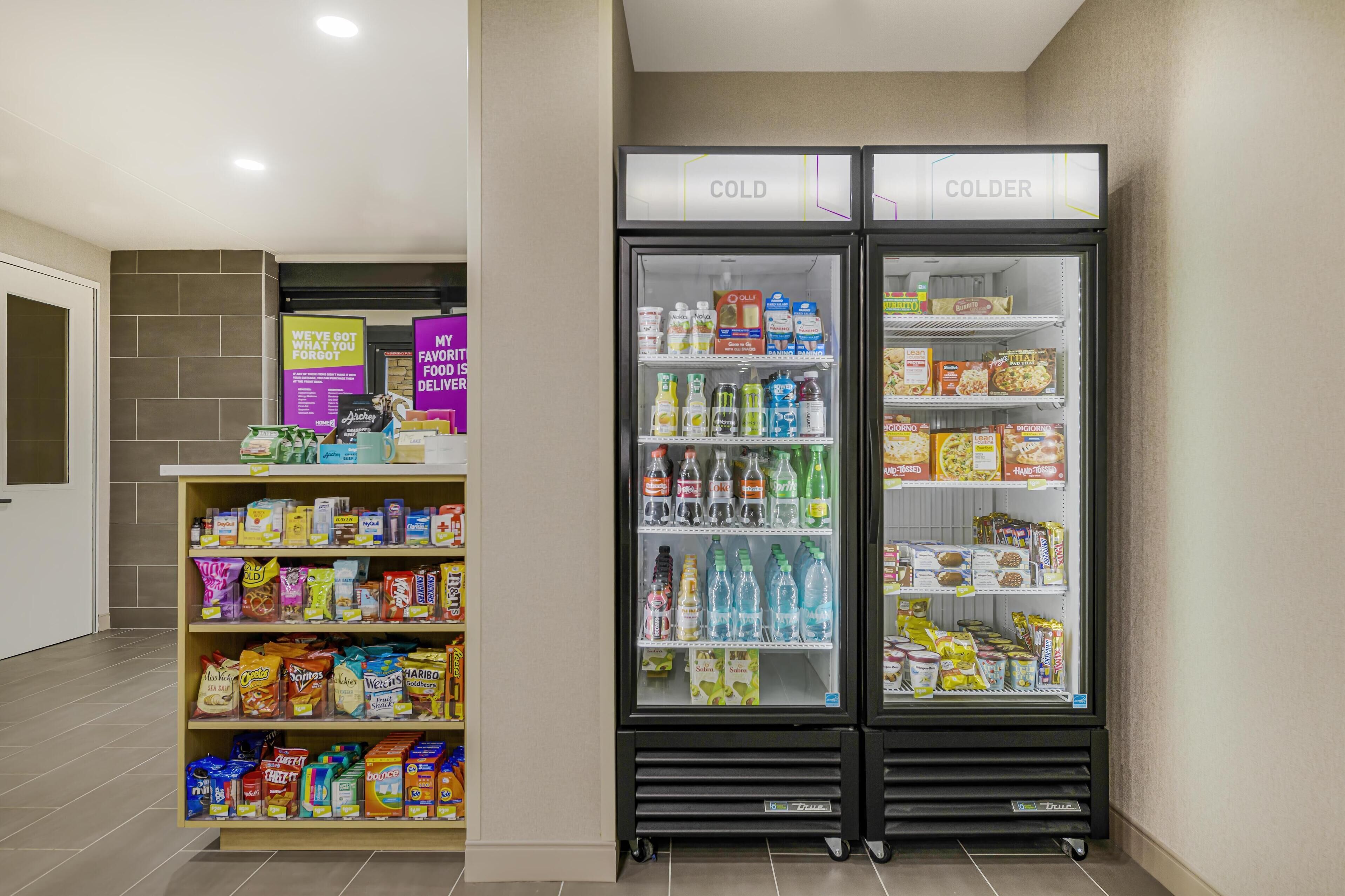 Mostrador refrigerado con aperitivos y bebidas, incluyendo varias opciones de papas fritas, cereales y refrescos embotellados.