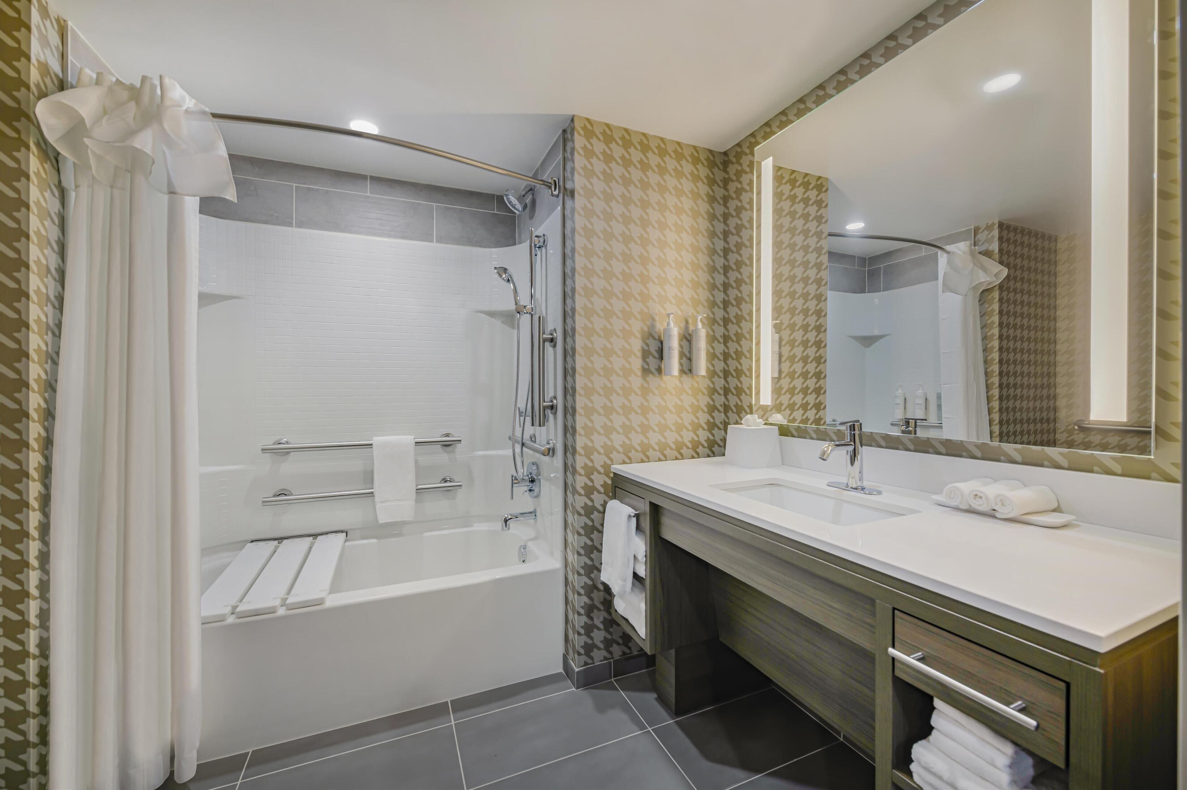 A modern bathroom with a walk-in shower, a double sink vanity, and a large mirror.