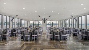 A spacious hall with rows of tables and chairs, large windows, and a view of the outdoors. - Home2 Suites By Hilton Guntersville (Guntersville)