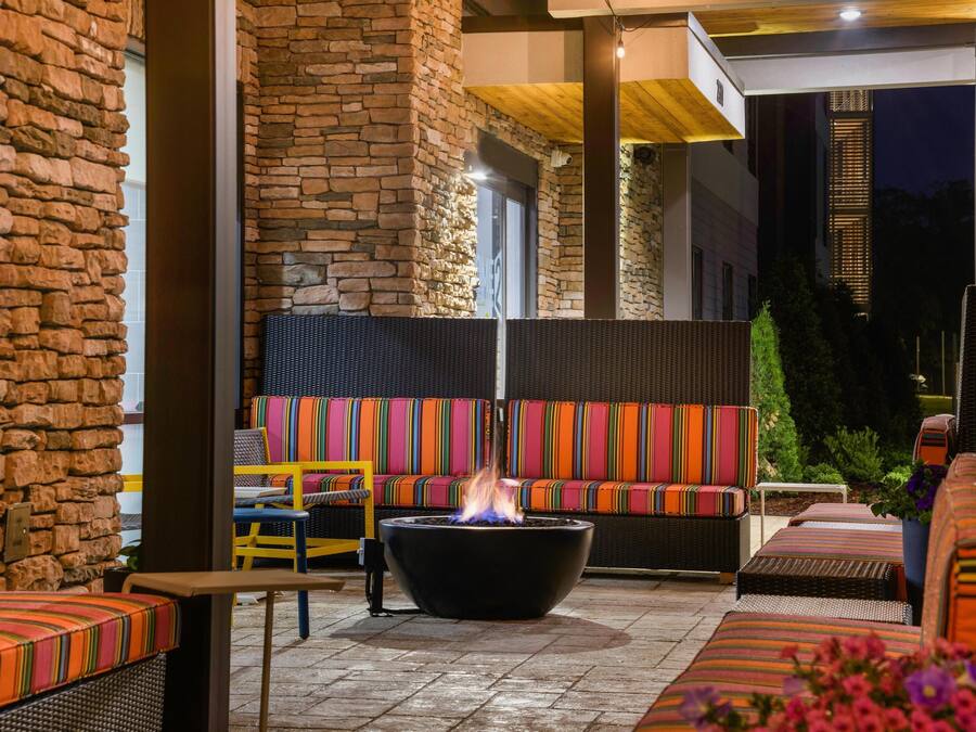 A patio area with stone walls, a fire pit, and colorful outdoor seating.