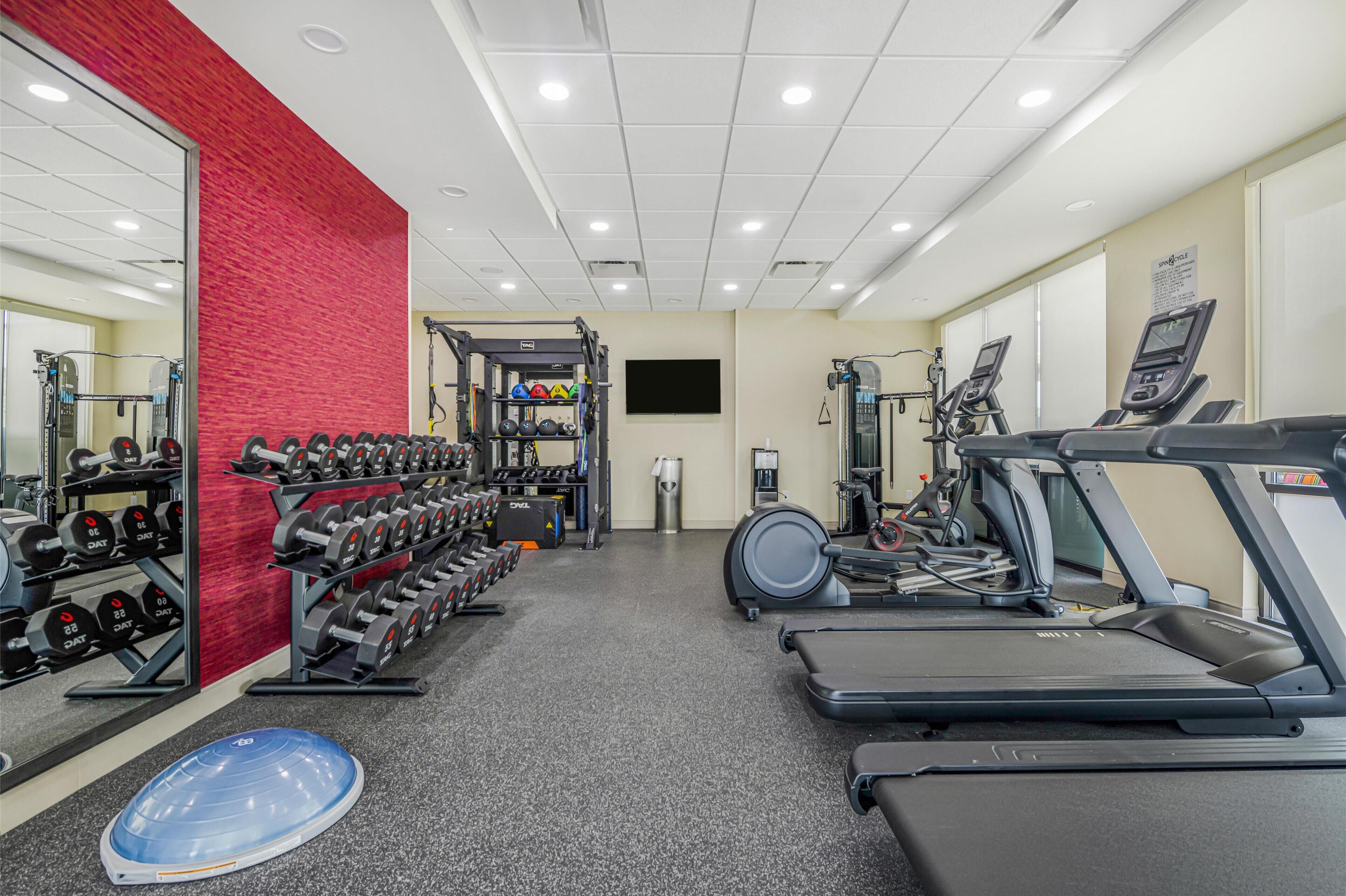 A gym with treadmills, dumbbells, and weight machines.