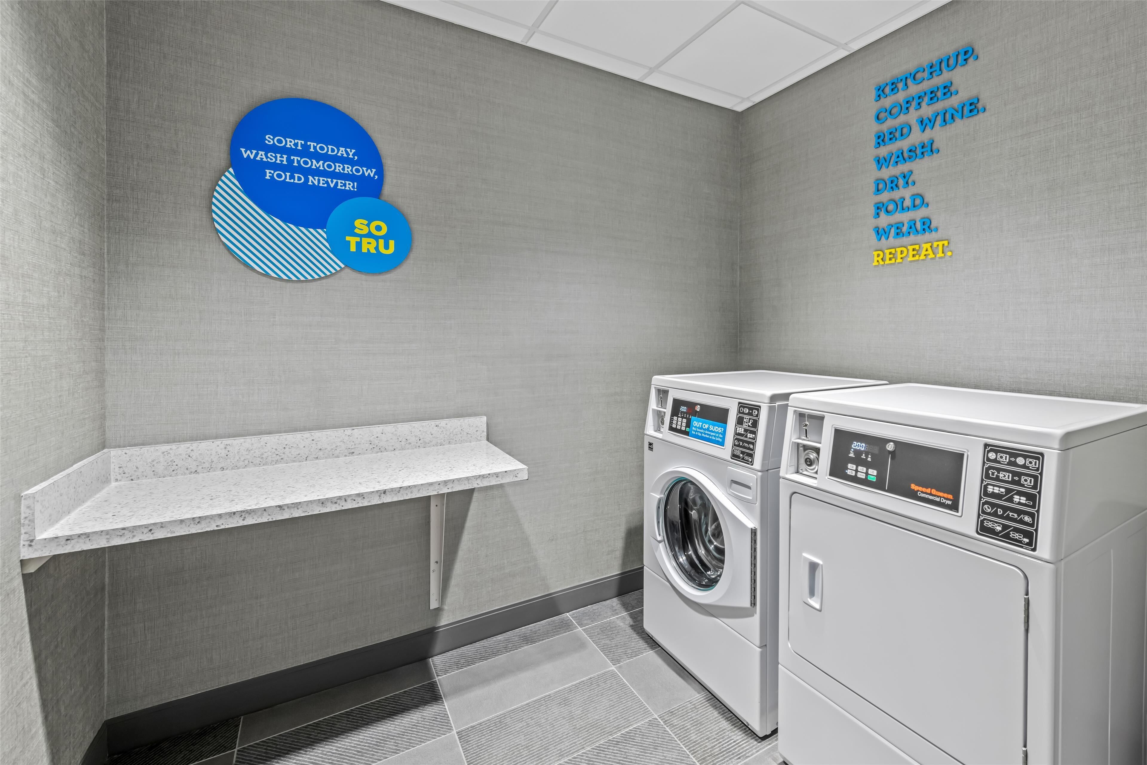 Een wasserette met een bord aan de muur en twee gestapelde wasmachines.