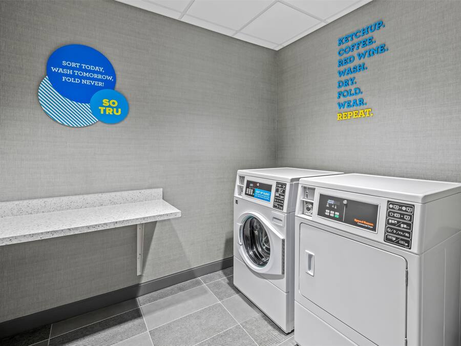 Een wasserette met een bord aan de muur en twee gestapelde wasmachines.