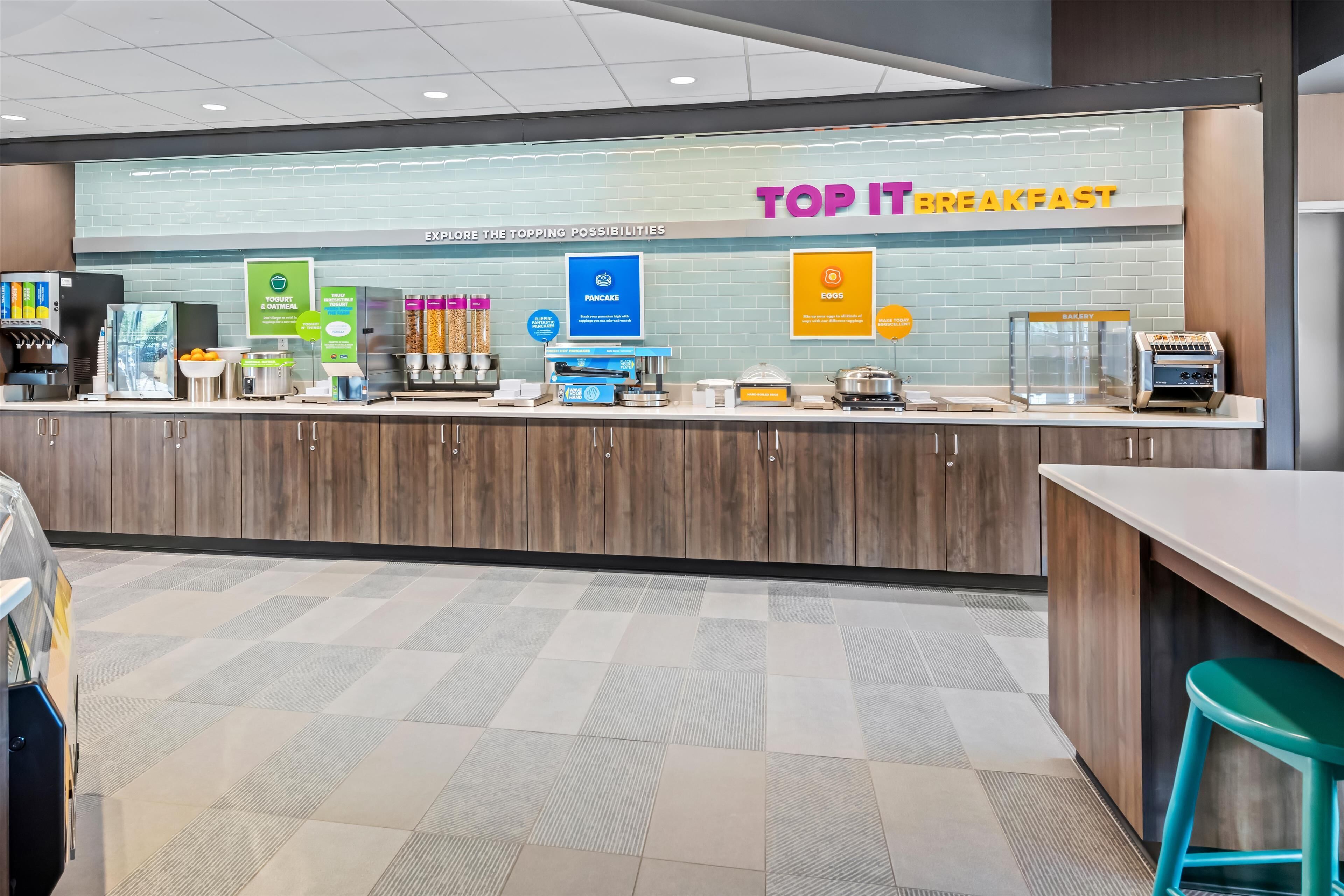 A breakfast area with a counter displaying various food options like yogurt, pancakes, and eggs.