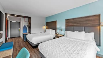 A hotel room with two beds, a desk, and a chair.