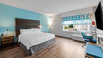 Een moderne hotelkamer met een groot bed, een bureau en een stoel.