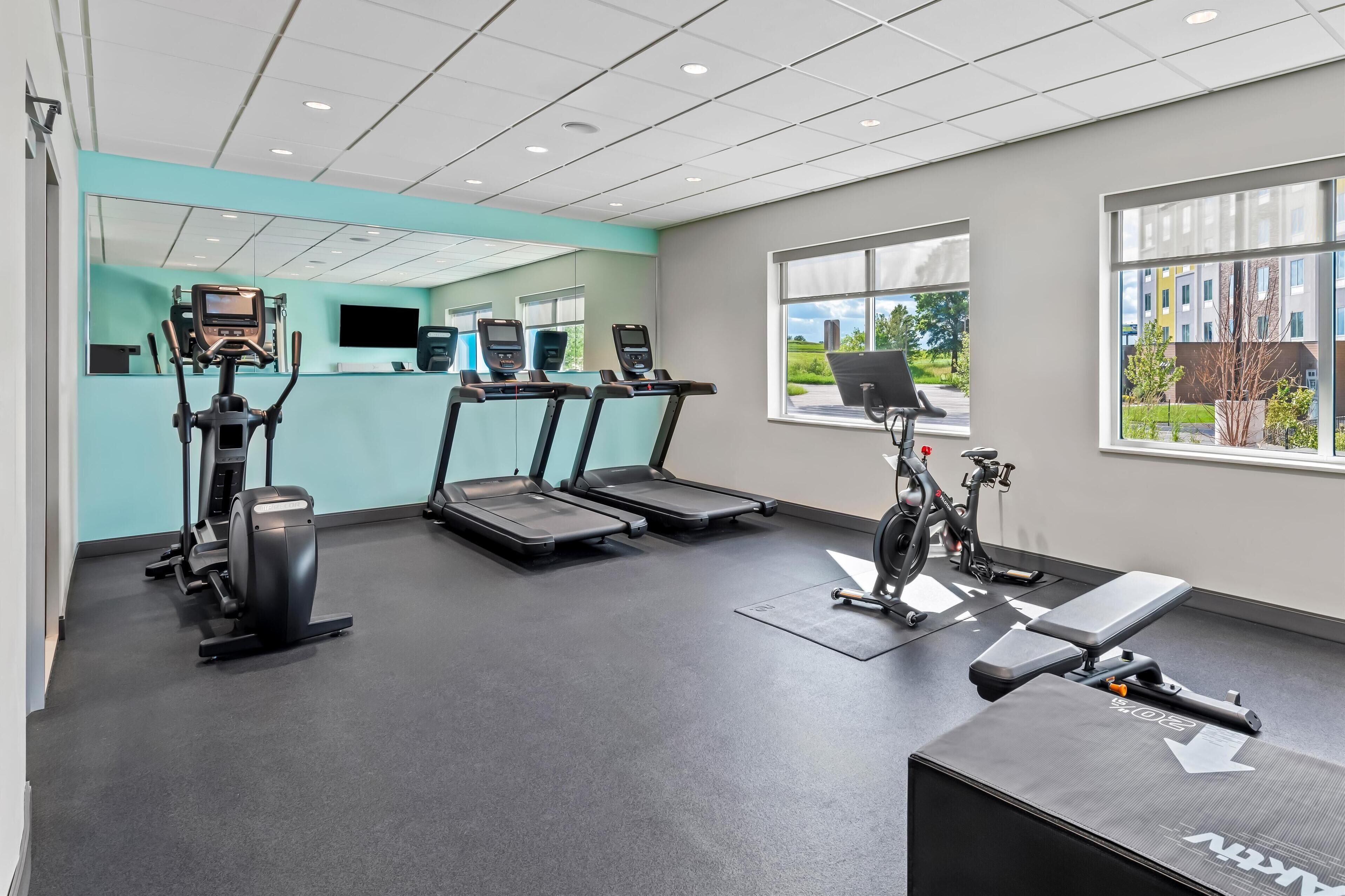 A modern gym with treadmills, a stationary bike, and weight machines.