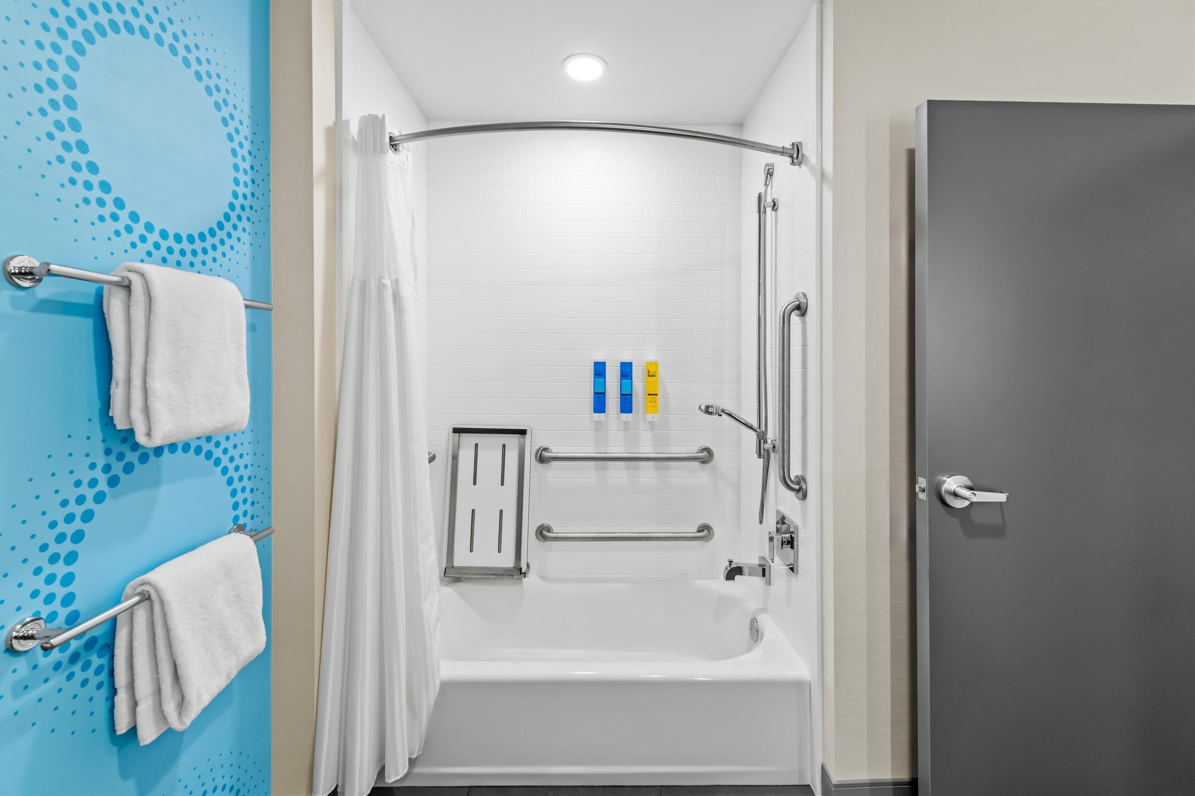 Une salle de bain moderne avec une baignoire blanche, une douche dotée d’une porte incurvée et une porte grise.