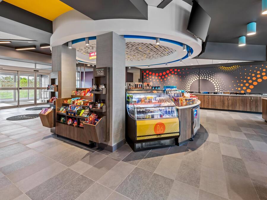 Ett modernt försäljningsområde med en kiosk som säljer snacks, ett kylskåp för att visa upp varor och en disk med drycker.