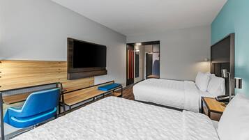 A hotel room with two beds, a TV mounted on the wall, a desk with a chair, and a small table with a keyboard.