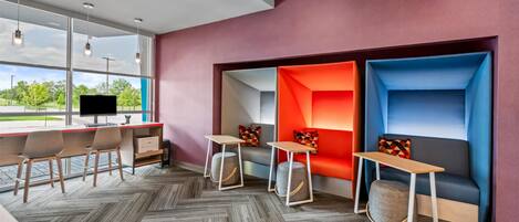 A modern office space with a herringbone-patterned floor, a red accent wall, and a large window offering a view of greenery.