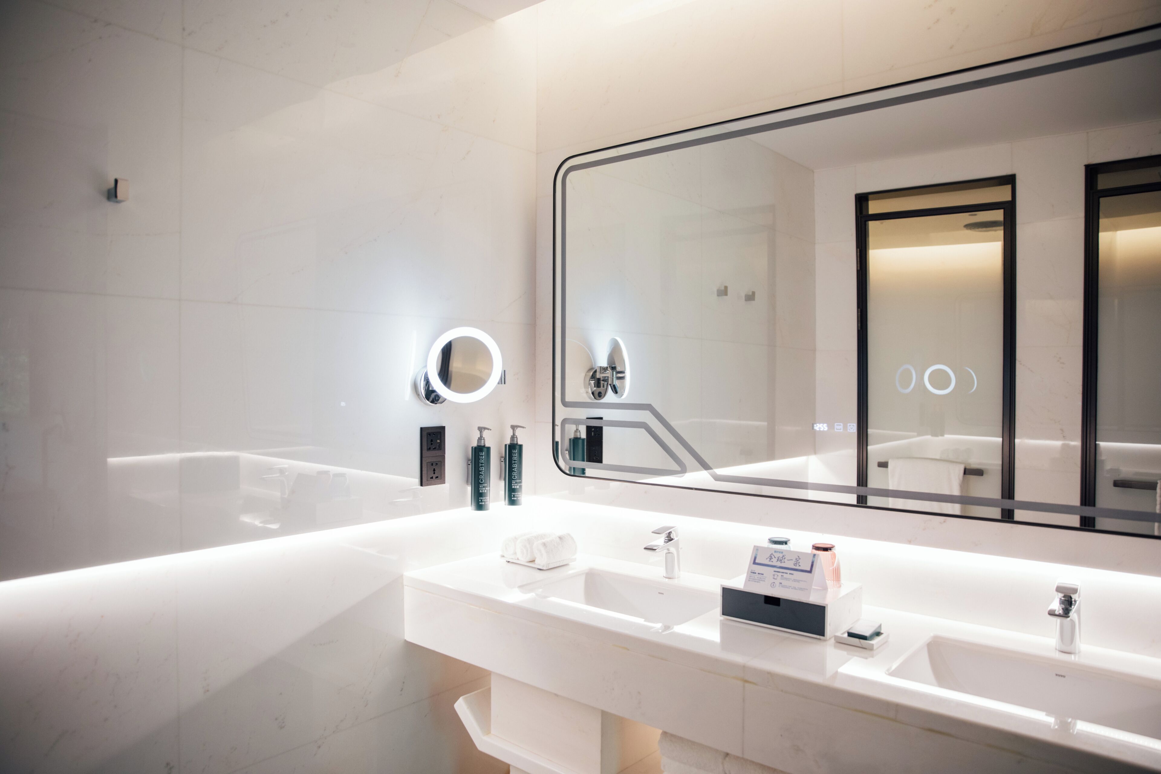 A modern bathroom with a large mirror, two sinks, and a bathtub.
