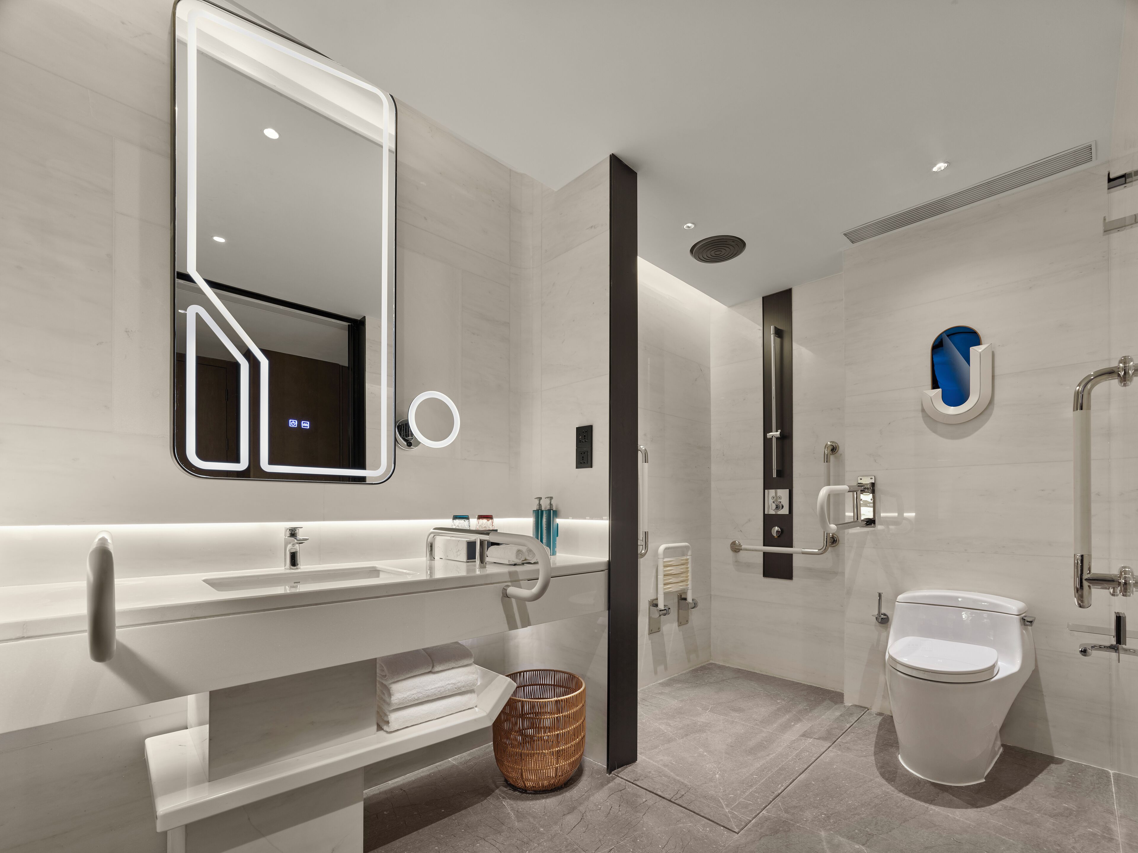 Un baño moderno con un espejo grande, un inodoro y un lavabo.