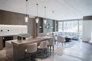 Una cocina moderna con una isla central, taburetes de bar e iluminación colgante.