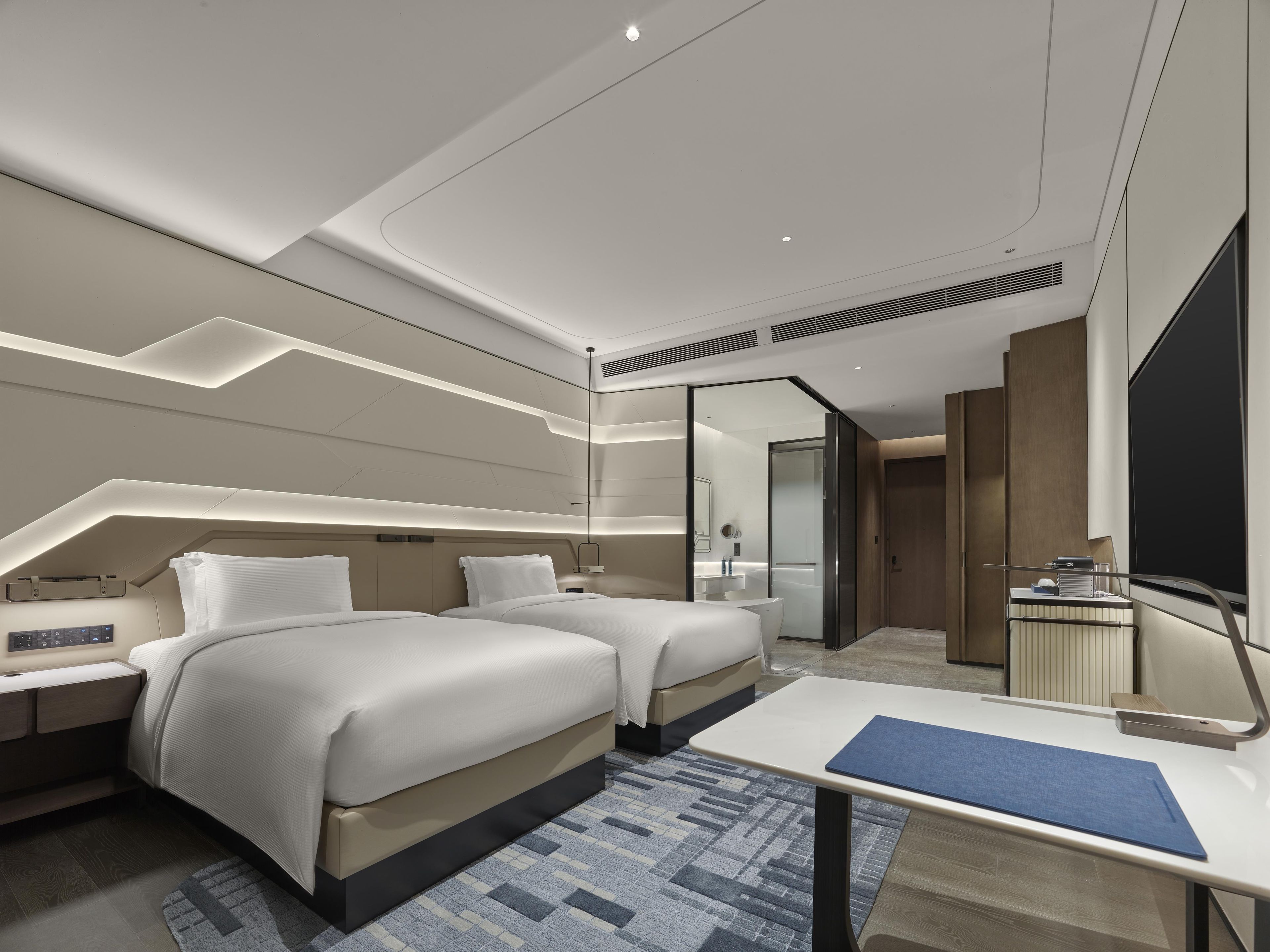 Habitación de hotel moderna con dos camas, un escritorio y un baño.