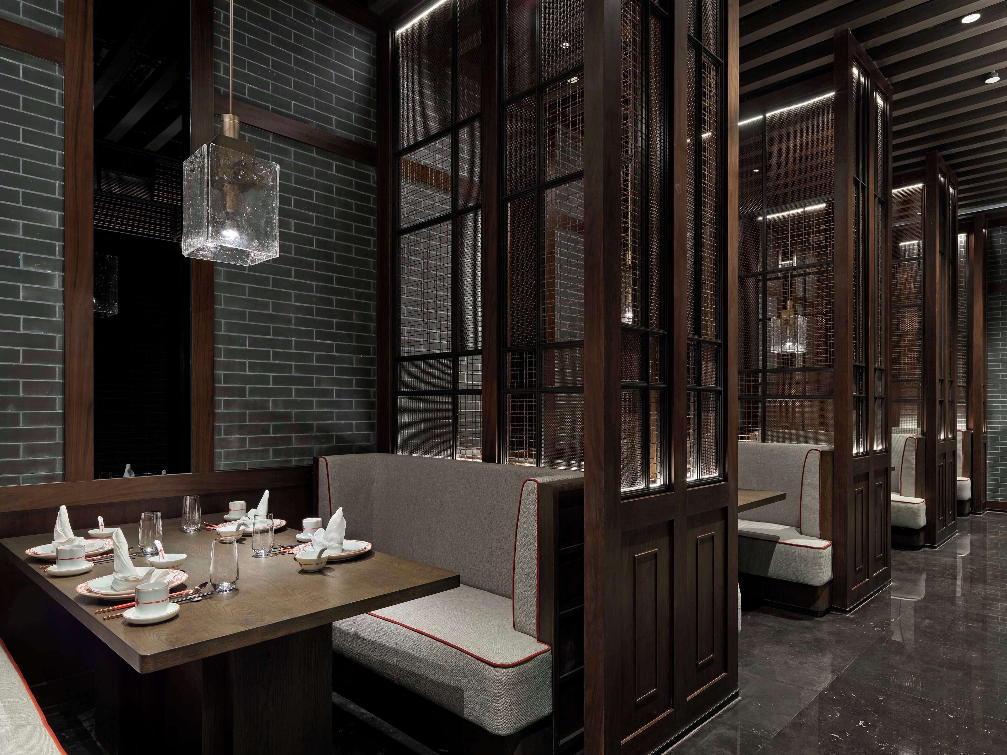 Un restaurante con cabinas de madera, pared de ladrillo y una lámpara colgante.