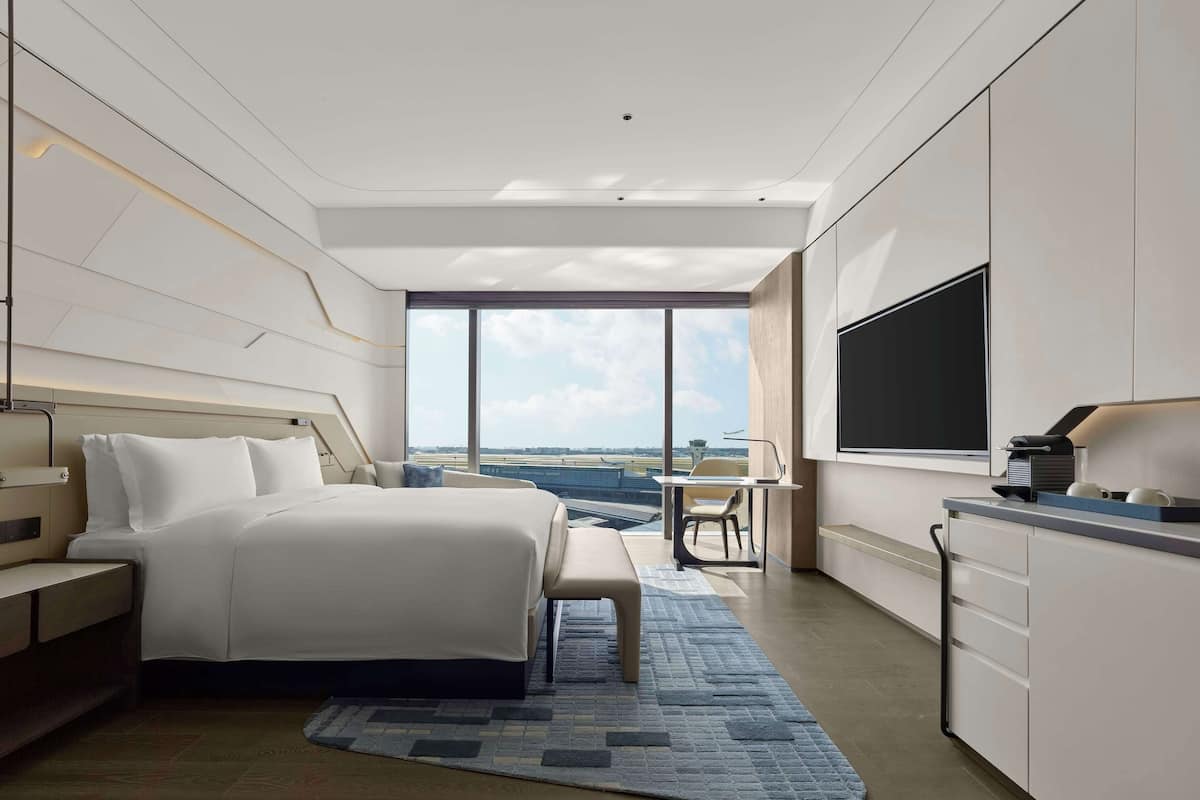 Ein modernes Hotelzimmer mit einem großen Bett, einem Schreibtisch und einem Fernseher.