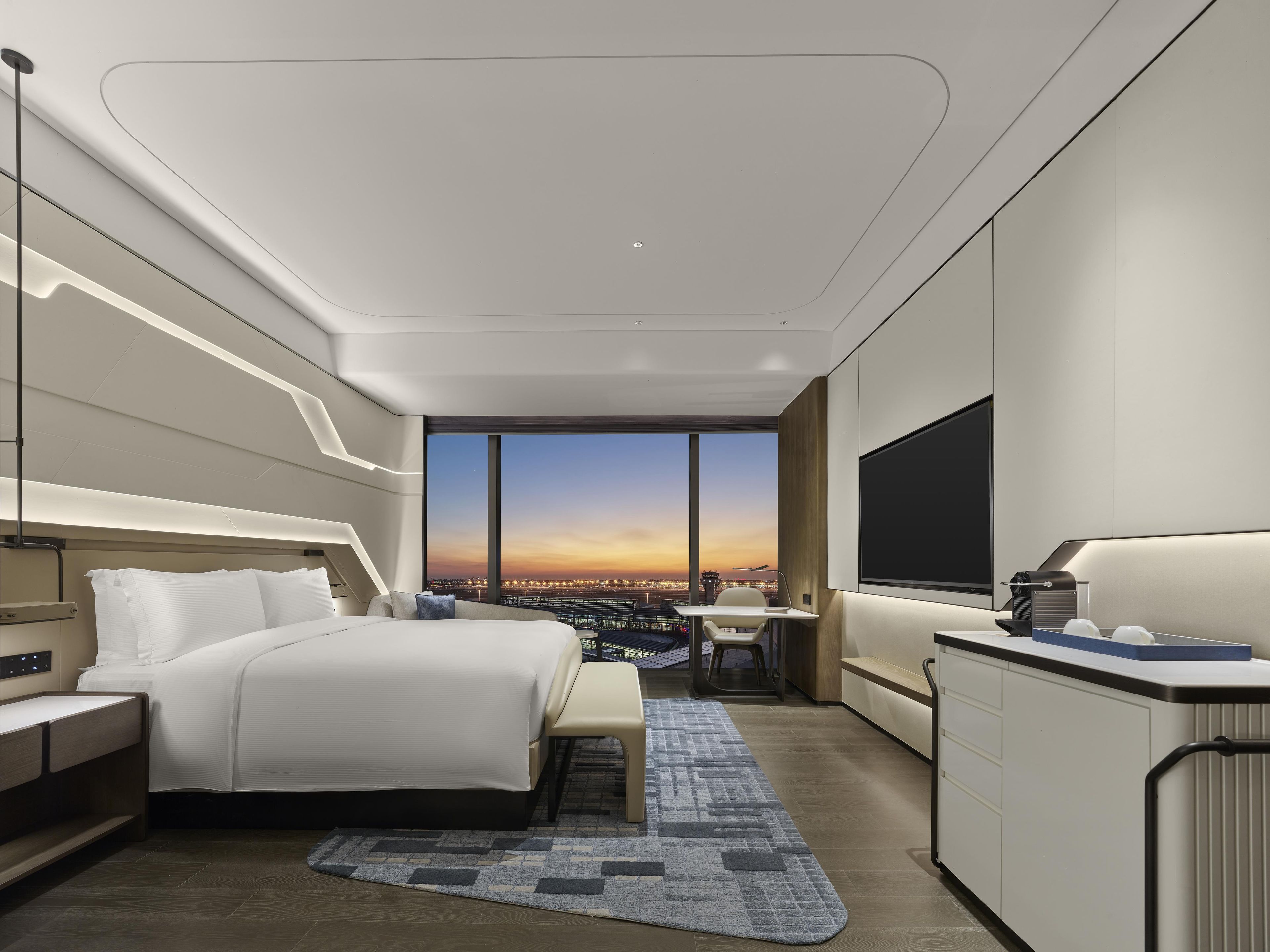 Una habitación de hotel moderna con una cama grande, un escritorio y vistas a la ciudad.
