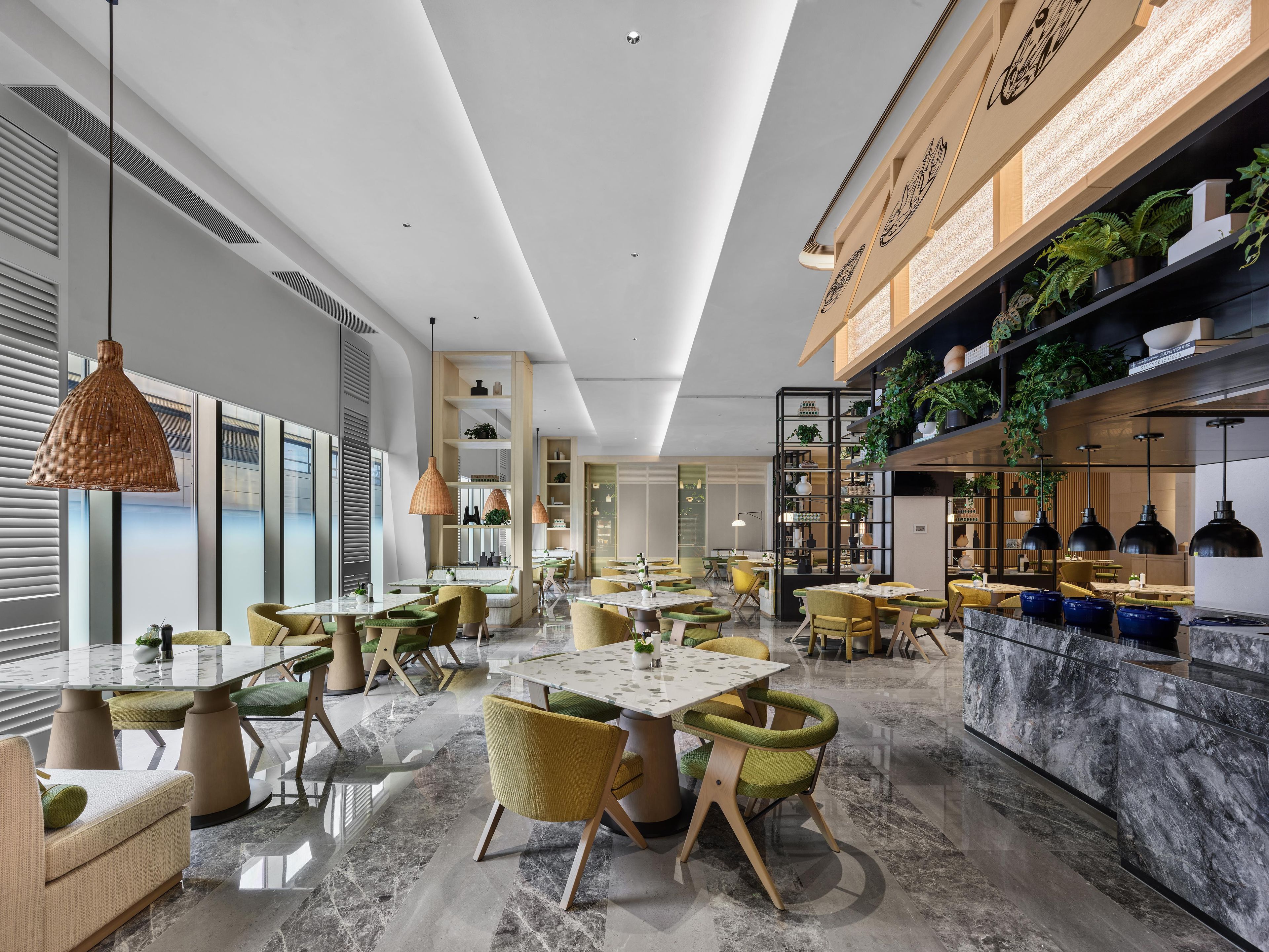A modern dining area with multiple tables and chairs, a marble floor, and a variety of plants on shelves.