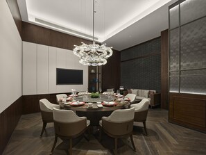 A modern dining area with a round table, chairs, and a chandelier.