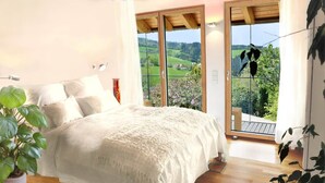 A bedroom with a large bed, a potted plant, and a balcony with a view of greenery. - Black Forest Loft 1, Unique Home, View (Horben)