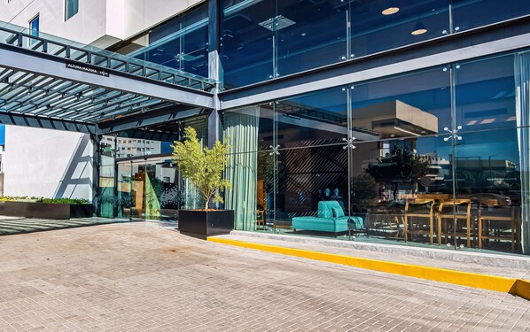A modern building with a glass facade, outdoor seating area, and a clear sky.