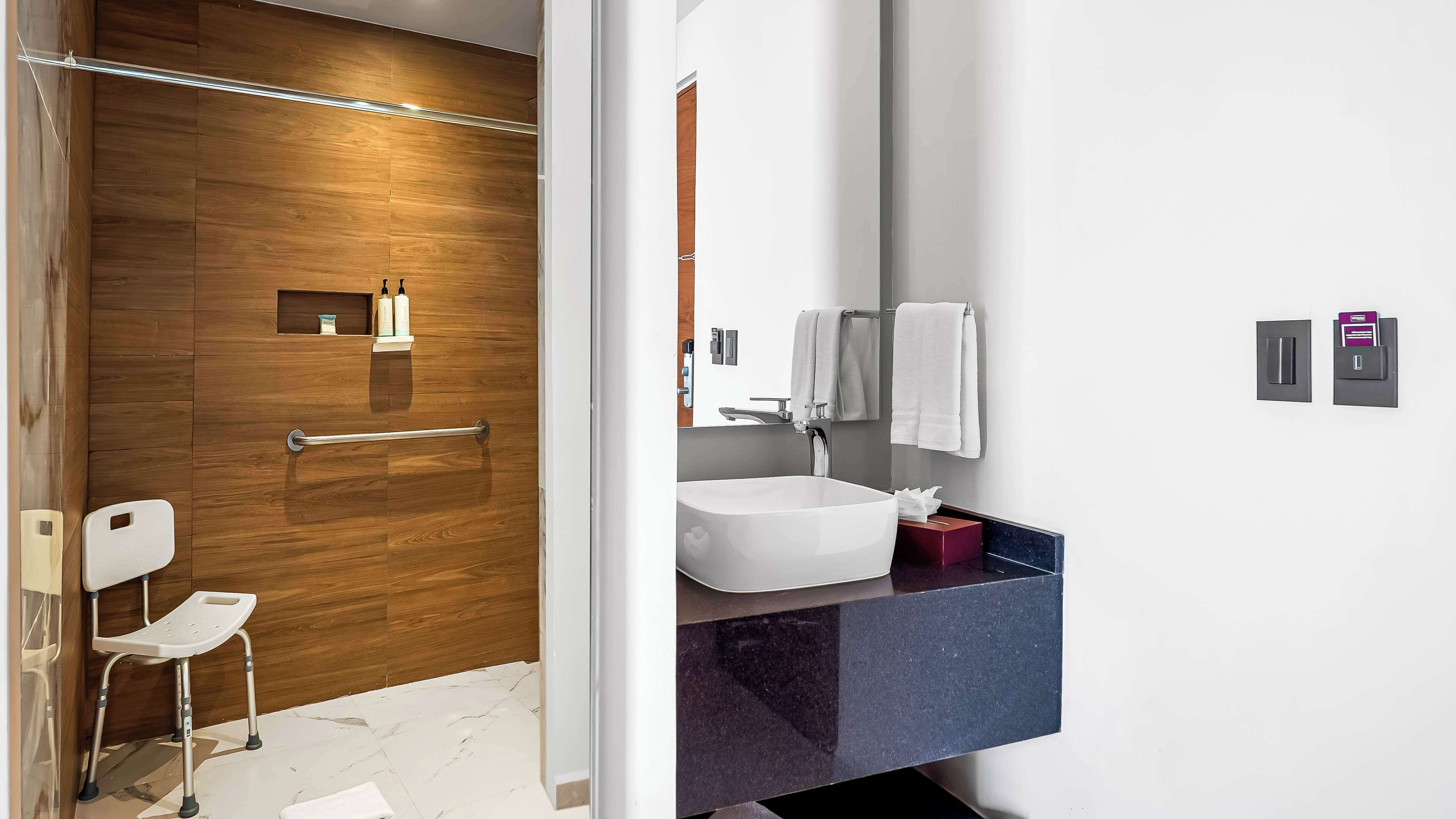 A modern bathroom with a wooden shower enclosure, a white sink, and a vanity with a mirror.