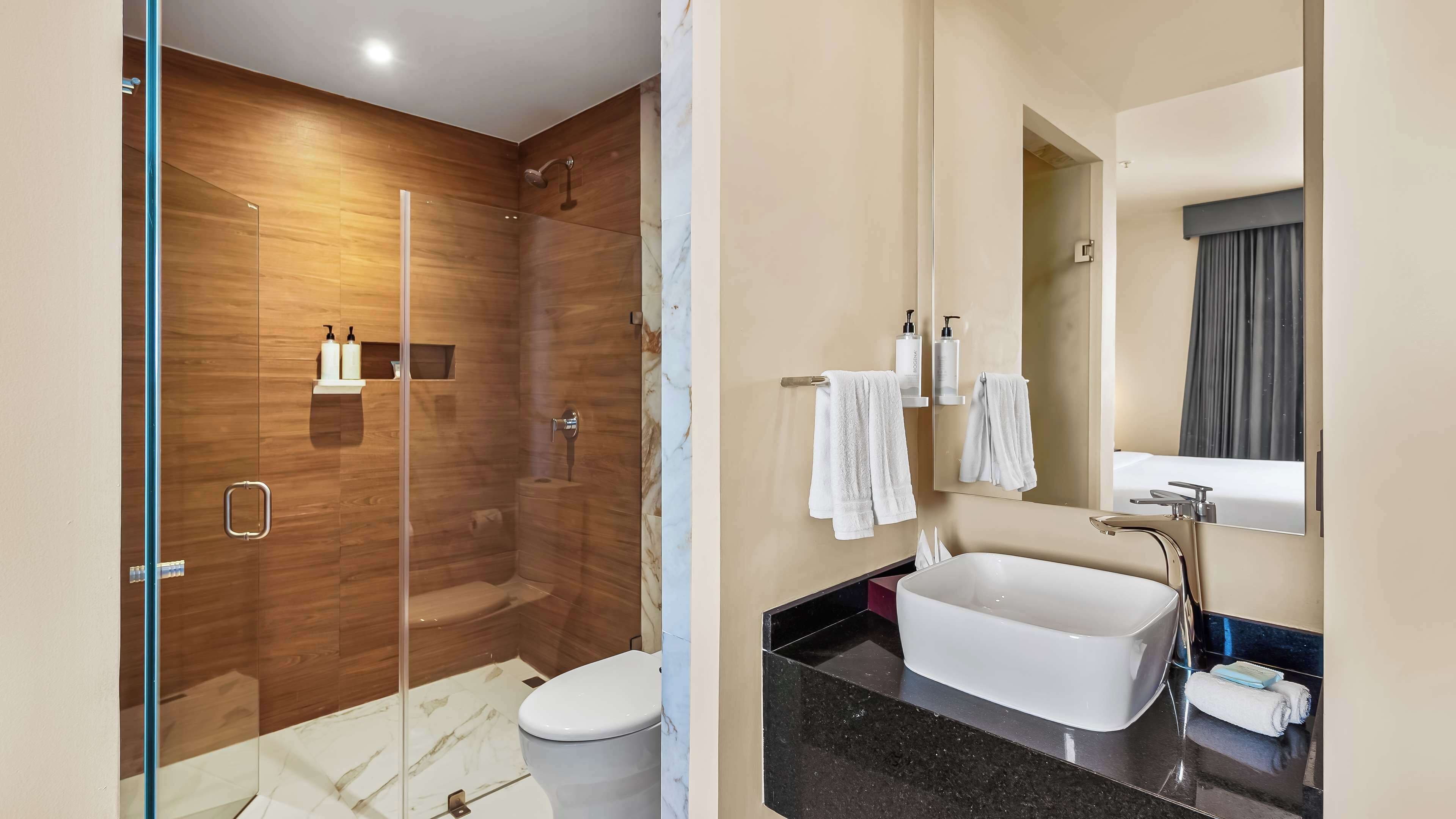 A modern bathroom with a glass-enclosed shower, a white toilet, a large freestanding bathtub, and a vanity with a mirror.