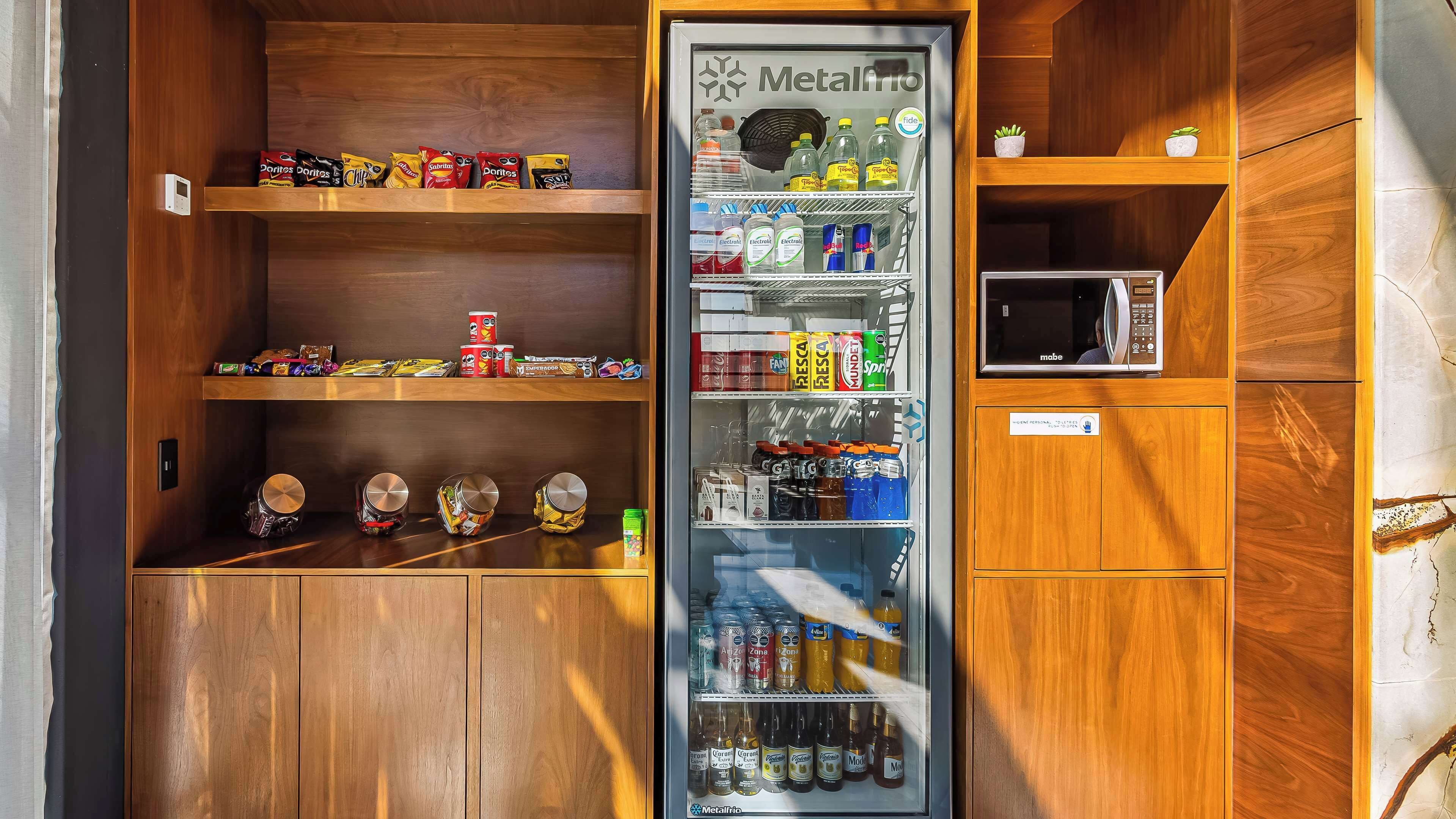 A vending machine stocked with snacks and beverages, a microwave, and a small potted plant.