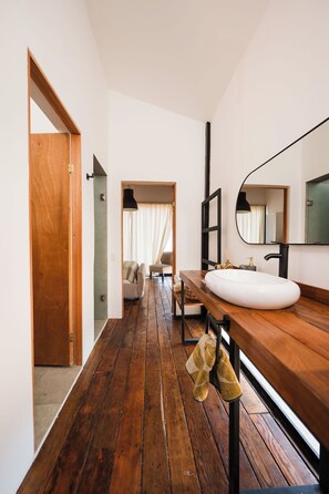 A modern bathroom with a wooden vanity, a large mirror, and a white sink. - Primario Hotel Boutique  (Valle de Guadalupe)