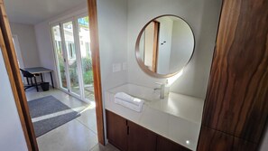 A modern bathroom with a large mirror, a sink, and a towel rack. - Modern California beach house, indoor-outdoor living, walk to the beach (San Diego)