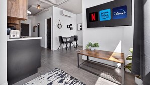 A modern kitchen with a built-in island, a dining area with a bench, and a wall-mounted TV displaying streaming services.