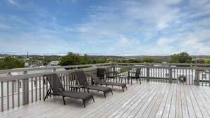 A wooden deck with outdoor furniture and a view of a town. - Loft 304 | Rooftop | Downtown (Rimouski)