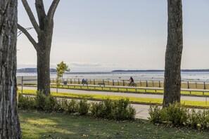 Un sentier bordé d’une rambarde, avec des arbres et une vue sur une étendue d’eau.