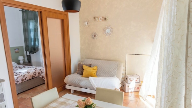 Ein gemütliches Zimmer mit einem Bett, einem Sofa, einem Tisch mit Blumenvase und einer Wand mit dekorativen Elementen.